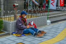 Man sitting on the floor in front of Edion Arena - Osaka - Japan Man sitting on the floor in front of Edion Arena - Osaka - Japan